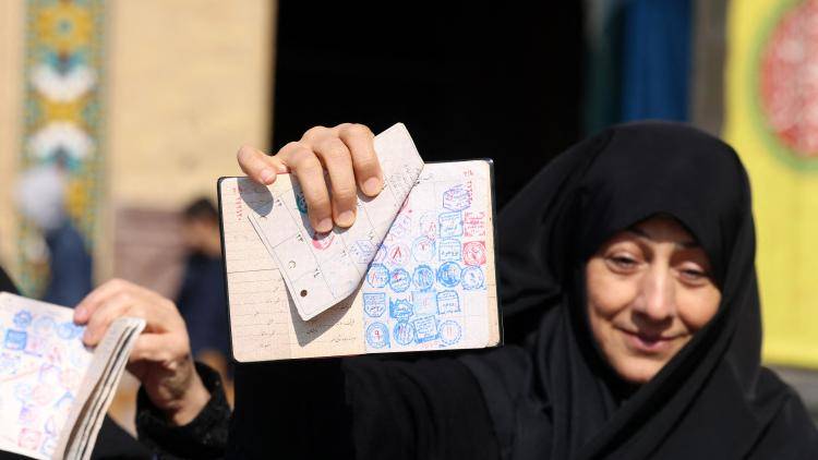 An Iranian woman shows a voting document as she waits in front of a polling station in Tehran on March 1, 2024
