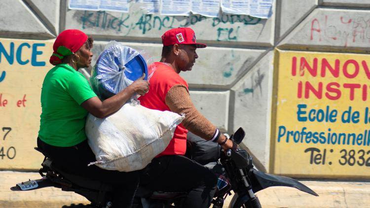 People on a motorcycle carry their belongings as they leave Port-au-Prince, Haiti, following gang violence in March 2024. 