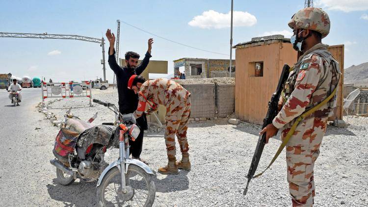 A Pakistani paramilitary ranger frisks a motorcyclist at a checkpoint. 