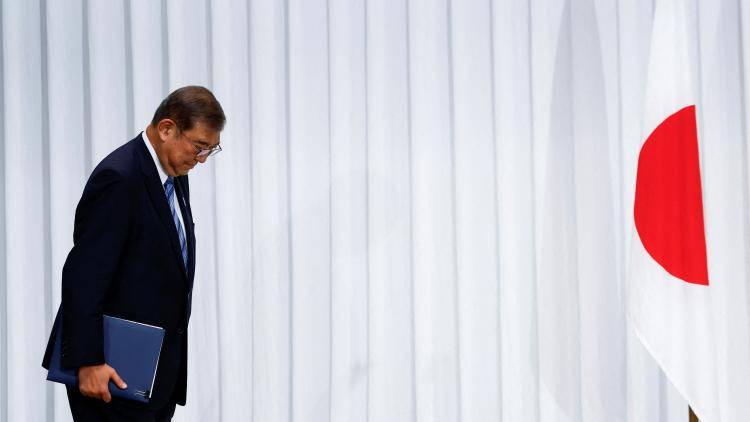 Shigeru Ishiba, Japan's prime minister, arrives for a press conference passing a Japan flag.