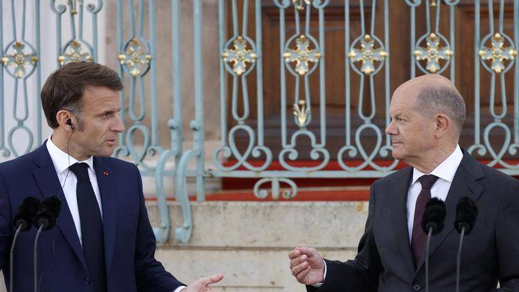two men in suits stand next to each other at podiums speaking
