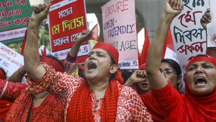 women in red clothing protest holding signs and with their fists in the air