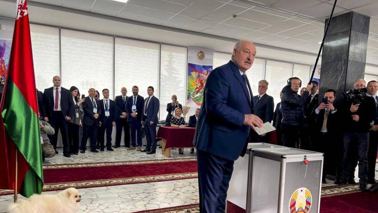 Alexander Lukashenka casts his ballot with his dog Umka at a polling station in the capital Minsk, Belarus with photographers in background