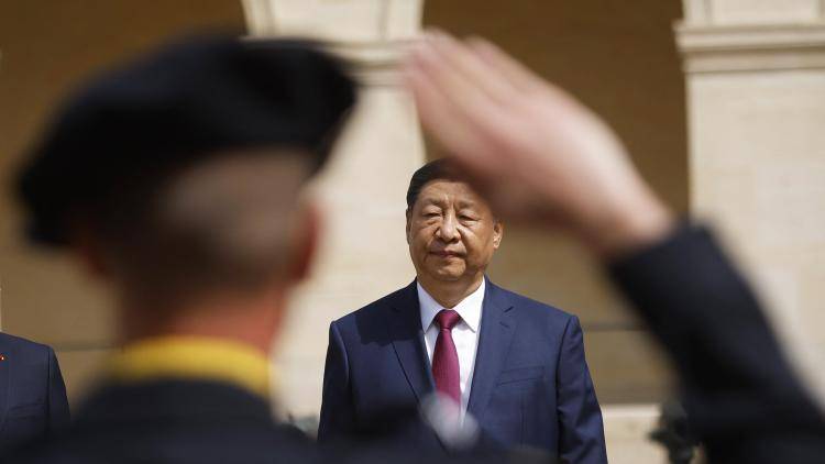 Chinese President Xi Jinping reviews troops who are saluting.