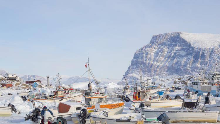 boats docked in frozen water with a person standing in the foreground