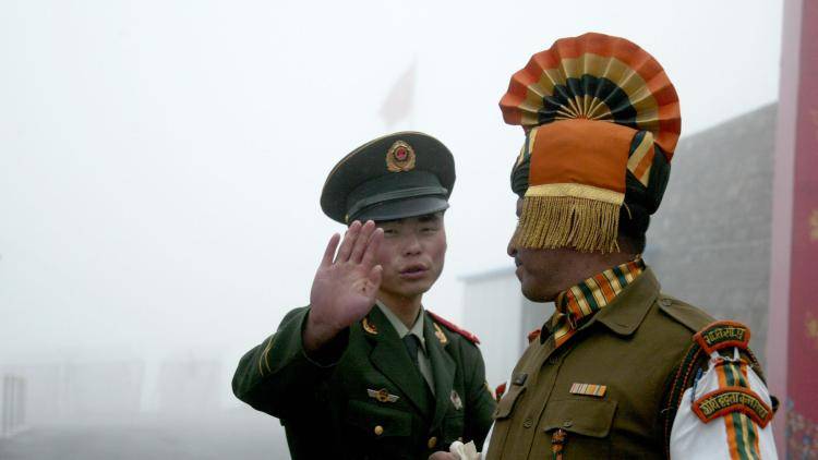 a Chinese solider holds his hand up next to an Indian solider