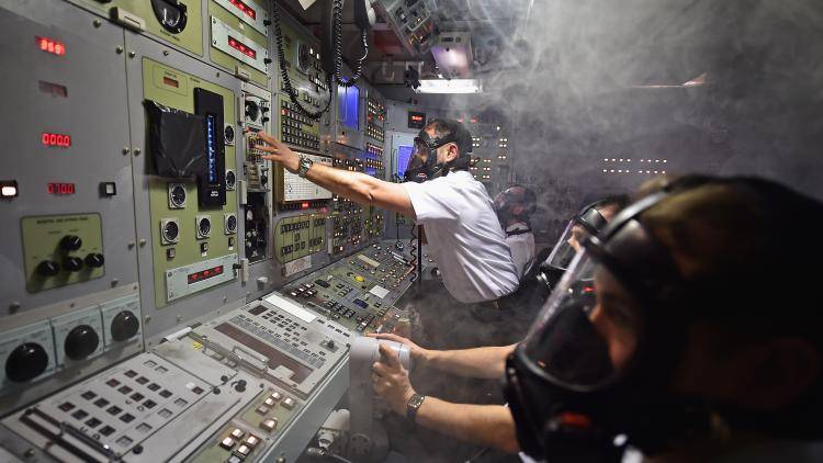people in gas masks operate controls in a nuclear submarine