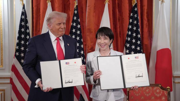 President Donald Trump and Japanese Prime Minister Sanae Takaichi hold signed documents with Japanese and US flags behind them