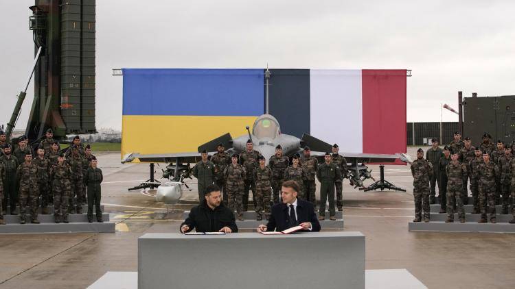 France's President Emmanuel Macron (R) and Ukraine's President Volodymyr Zelensky (L) sign an agreement at the Villacoublay air base near Paris.