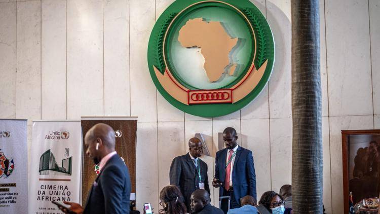 Delegates stand beneath a large African Union sign at the 38th African Union (AU) Summit in Addis Ababa on 15 February 2025 