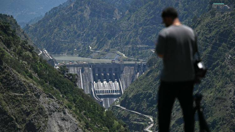 A journalist standing against the backdrop of the Baglihar Dam, on the river Chenab in the Ramban district of Jammu and Kashmir. 