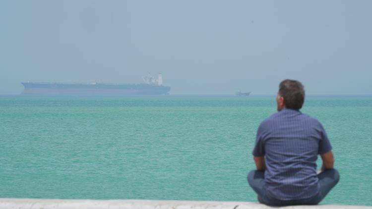 A man looks at shipping in the Strait of Hormuz