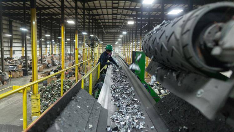 A worker sorts metal recyclable waste at a plant