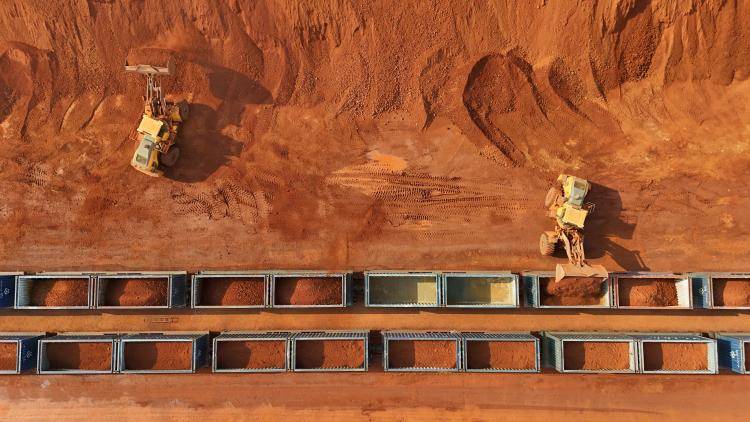 A birds eye view of Yellow vehicles loading minerals onto train compartments