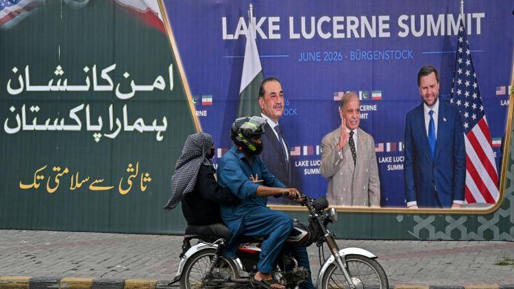 A family rides past a billboard featuring Pakistan's Prime Minister Shehbaz Sharif, Pakistan's Chief of Army Staff Field Marshal Asim Munir and the US Vice President JD Vance. 