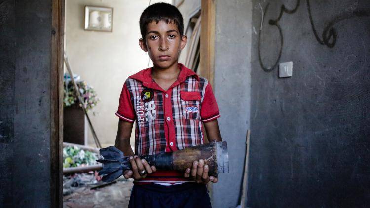 Ahmed, a Gazan boy, holds an Israeli mortar shell