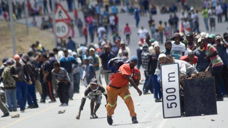 Striking farmworkers throw stones at police during a protest. Photo: Rodger Bosch/AFP/Getty Images