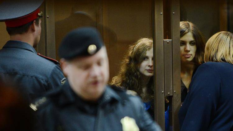 Maria Alyokhina and Nadazhda Tolokonnikova, two members of Pussy Riot, speak with their lawyer from a glass-walled cage in a court in Moscow. Photo: AFP/Getty Images