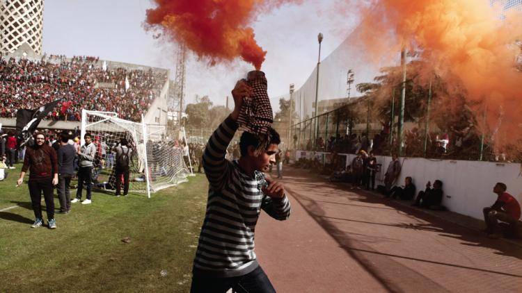 An Ahly Ultra supporter celebrates with a smoke bomb
