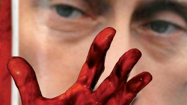 The painted hand of an Avaaz activist in front of a picture of Vladimir Putin during a protest against his support for the Syrian regime outside the UN Security Council building. Photo: Timothy A.Clary/AFP/Getty Images