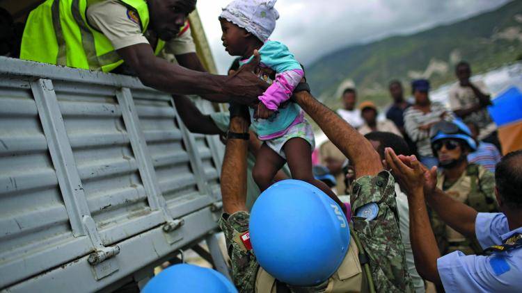UN Soldiers and an aid worker lift a little girl up into a UN truck in Port-au-Prince, Haiti. 