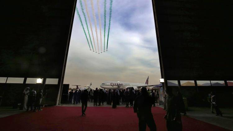 A Qatar Airways plane on the tarmac as Saudi falcon Hawk Mk 65 aircrafts perform during the Kuwait aviation show in January 2018