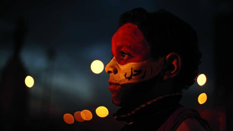 A boy has his face painted with the colours of the Egyptian flag standing near a barricade in Tahir Square.
