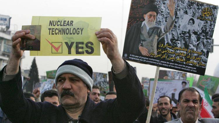 An Iranian man carries a placard in support of nuclear technology during a rally to mark the 28th anniversary of the Islamic revolution