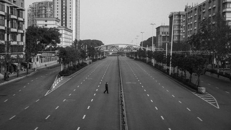 A man cross an empty highway road on February 3, 2020 in Wuhan, Hubei province, China (Photo by Getty Images).