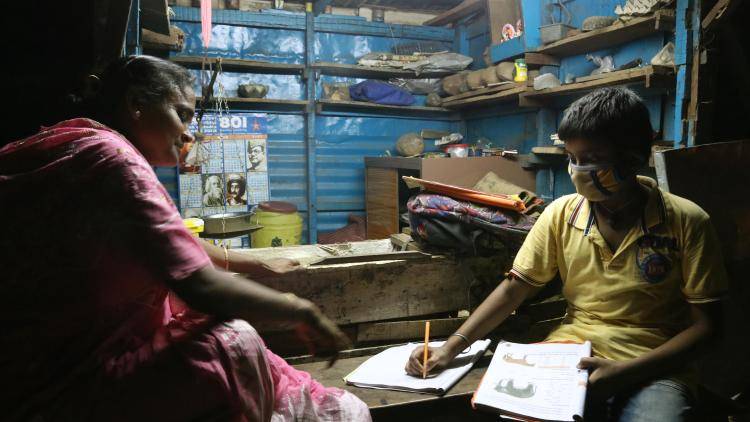 A mother teaching her son in a shop during lockdown in Kolkata, India