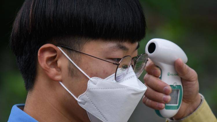 Students wearing face masks undergo a temperature check in Seoul 