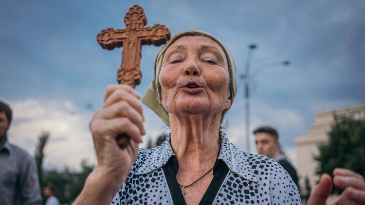 A woman prays during a protest against the Romanian government