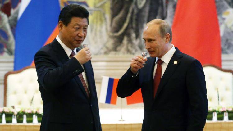 Presidents Vladimir Putin and Xi Jinping toast each other with vodka