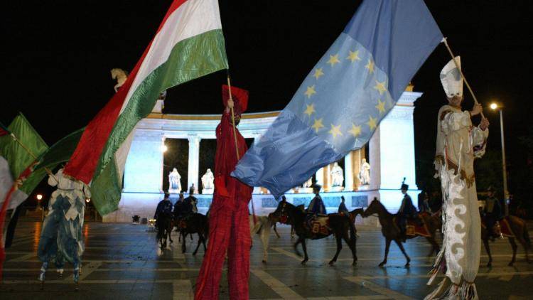 Hungarian men on stilts dancing with EU and Hungarian flags at the Heros square of Budapest