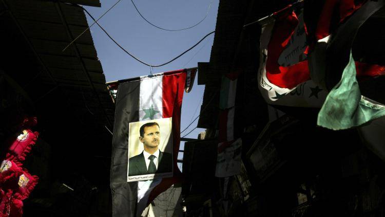 Syrian and Iraqi flags with posters of the Syrian president hang in the old streets of Damascus
