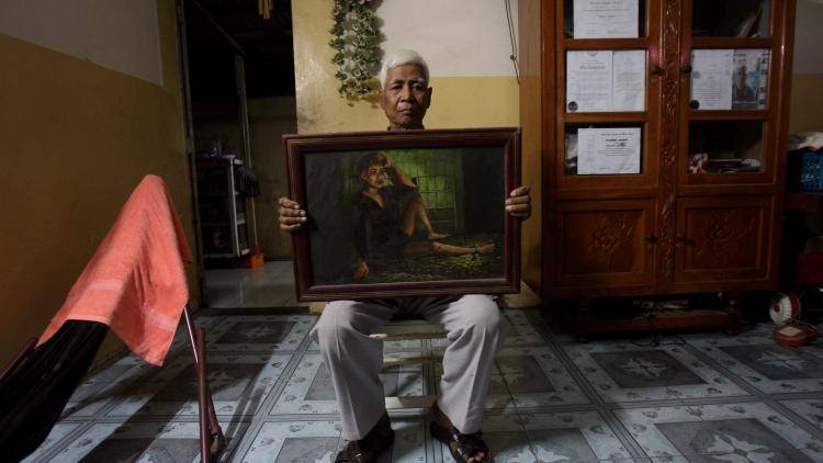 Vann Nath witness, artist and survivor of the Khmer Rouge regime holds one of his paintings