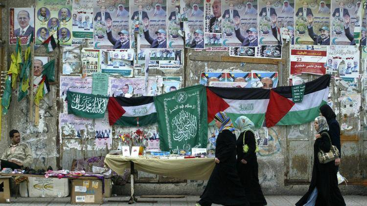 Palestinian girls walk past the green flags of the newly ruling Hamas party