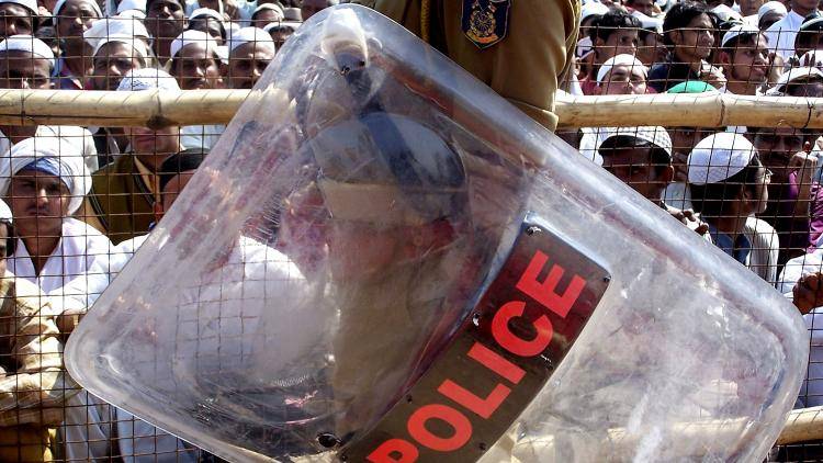 A riot policeman stands guard beside protesters demonstrating against the planned visit of U.S. President George W. Bush in New Delhi