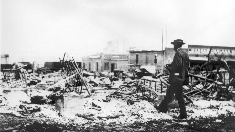 A man walks among the ashes of the Greenwood commercial district