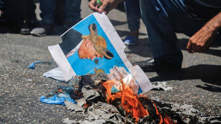 An image of Donald Trump defaced by shoes is burnt in protest in the West Bank
