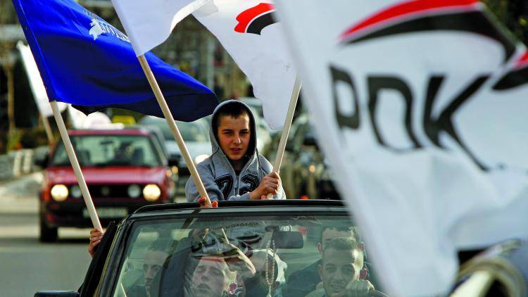 Supporters of the Democratic Party of Kosovo wave party flags. 