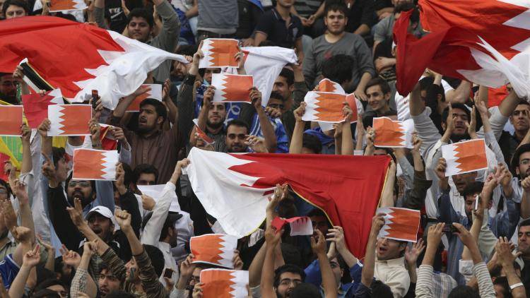 Protestors hold Bahraini flags in protest against Saudi and Bahraini leaders for cracking down on Bahraini opposition, at the Azadi stadium in Tehran, Iran. 