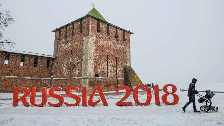 A man pushes a stroler past a FIFA World Cup 2018 emblem placed in front of the Nizhny Novgorod's Kremlin
