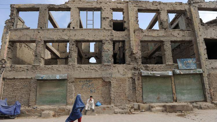 A burqa-clad Afghan woman walks past the ruins of a building destroyed during the civil war in Kabul.