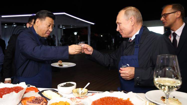 Presidents Xi and Putin eating Russian pancakes in 2018