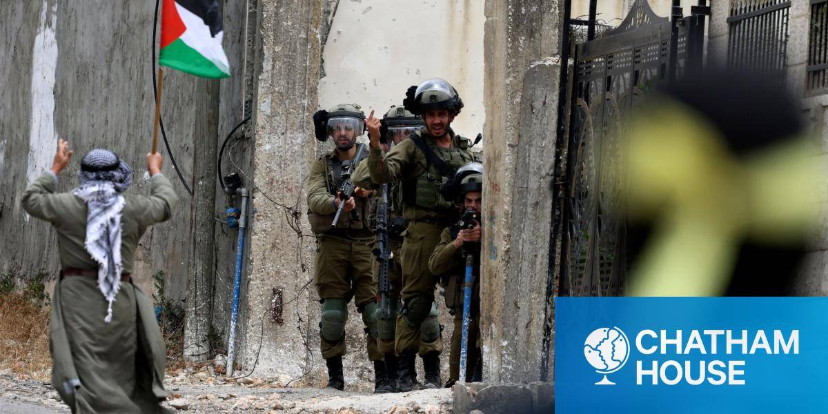 A demonstrator brandishing a Palestinian national flag walks past Israeli troops in the village of Kfar Qaddum, near the Jewish settlement of Kedumim.