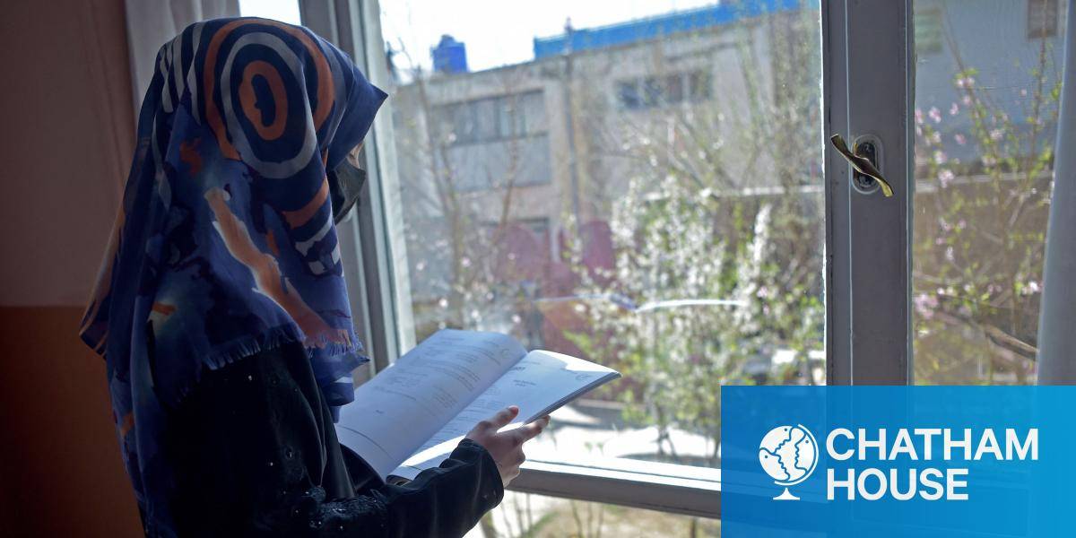 A twelfth grade student from a secondary school reads a book at her residence in Kabul 