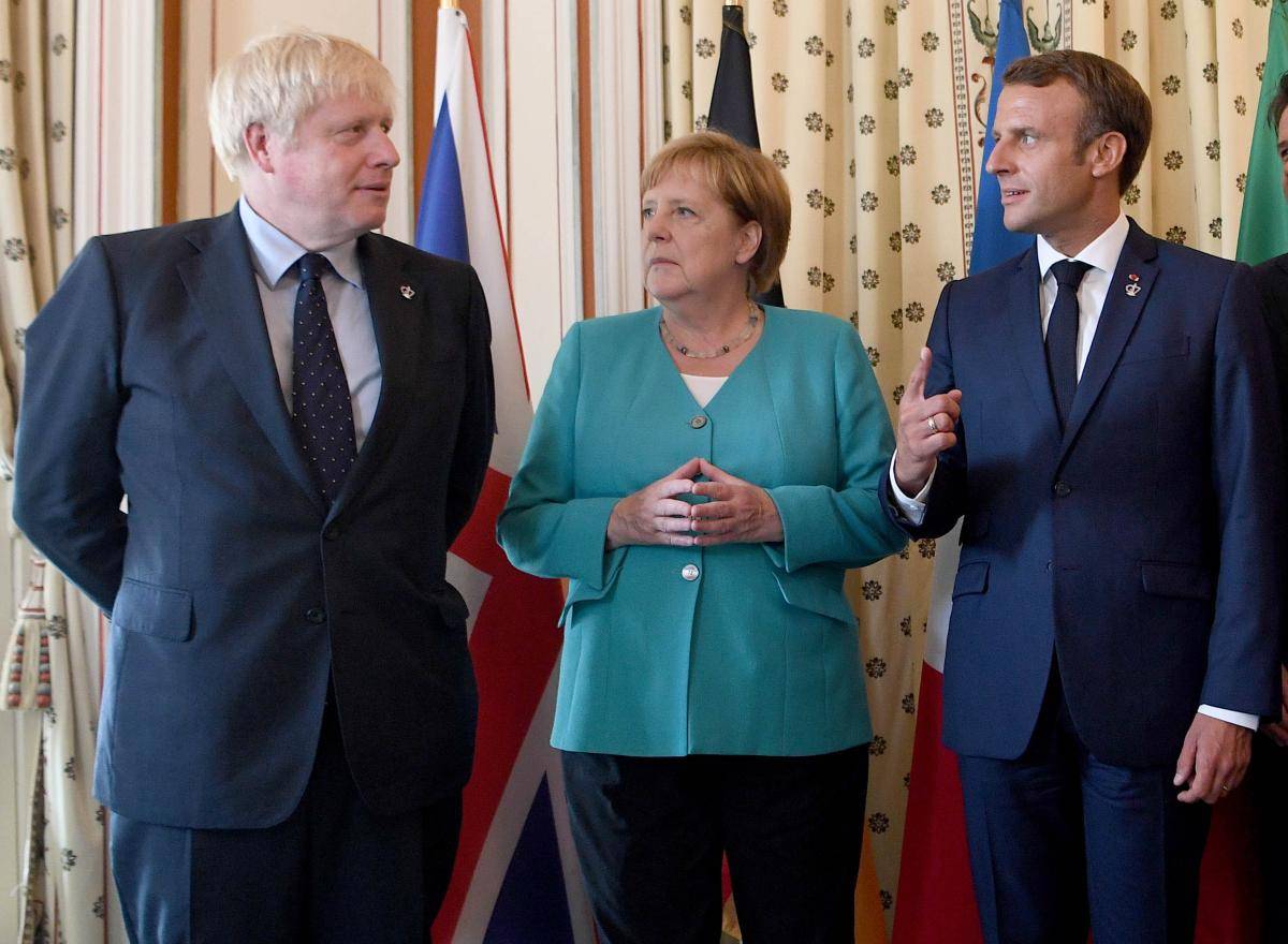 British Prime Minister Boris Johnson, German Chancellor Angela Merkel and French President Emmanuel Macron pose during a G7 coordination meeting at the Hotel du Palais on 24 August 2019 in Biarritz, France. Photo credit: Pool/Getty Images