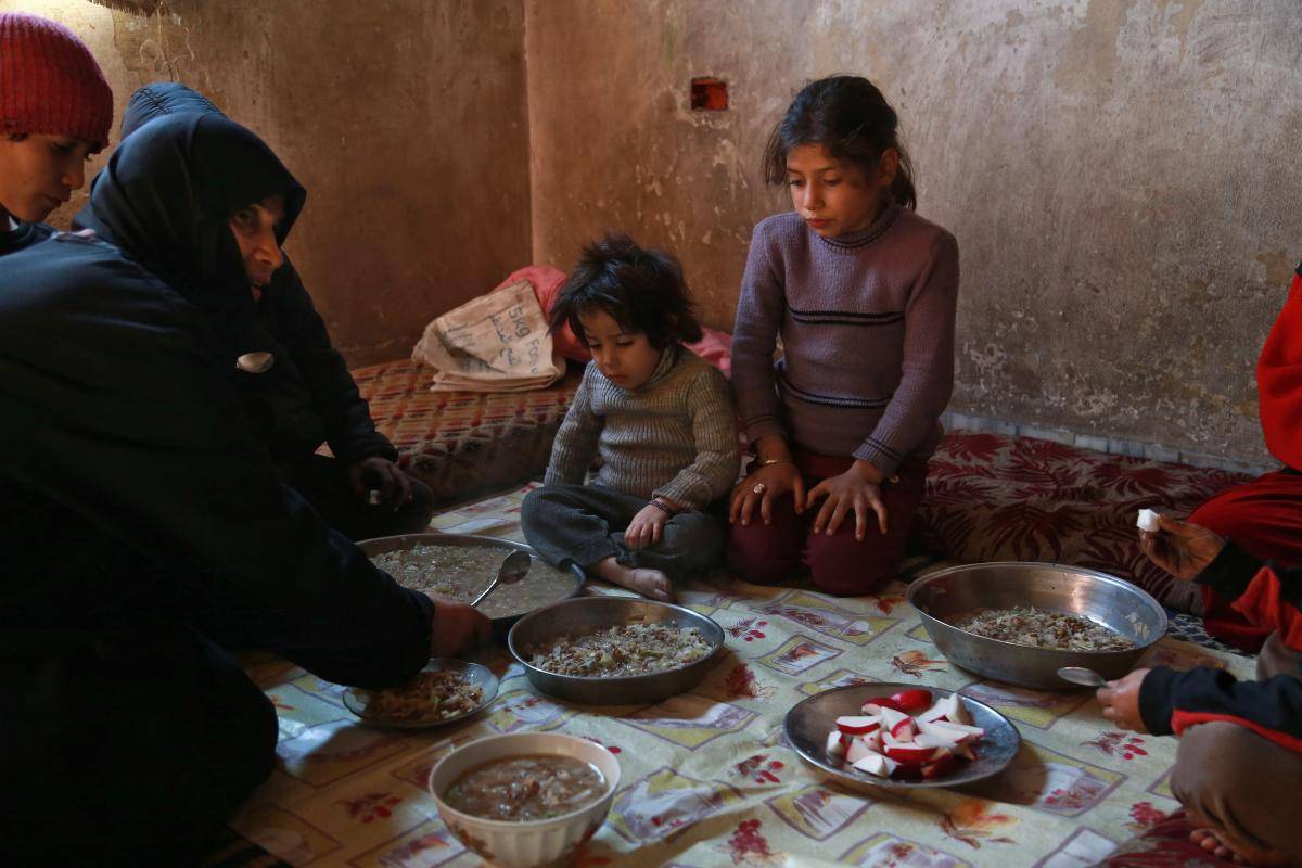 A Syrian family gather to eat a plate of corn and cabbage in Saqba, in the besieged rebel-held Eastern Ghouta area near Damascus on 6 November 2017. Photo: Getty Images