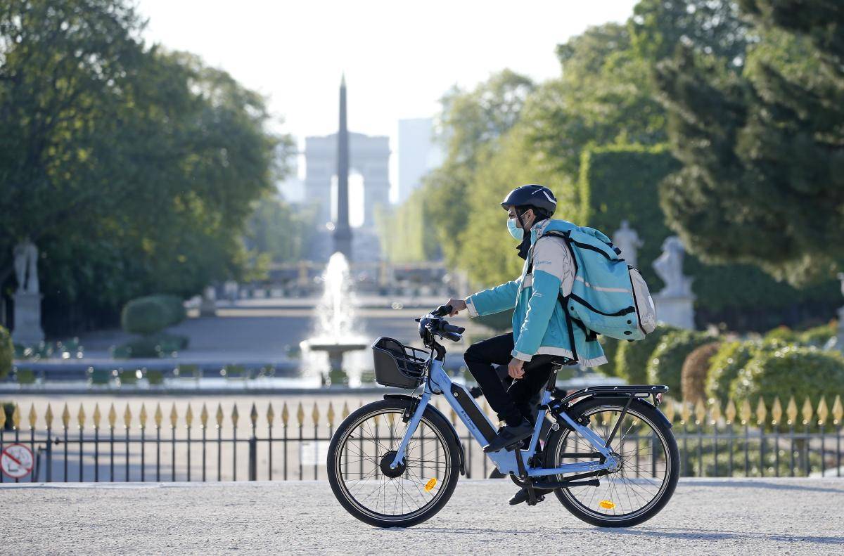 A Deliveroo rider wearing a protective mask rides his bike in the Jardin des Tuileries, Paris, 15 April 2020. Photo: © Chesnot/Getty Images